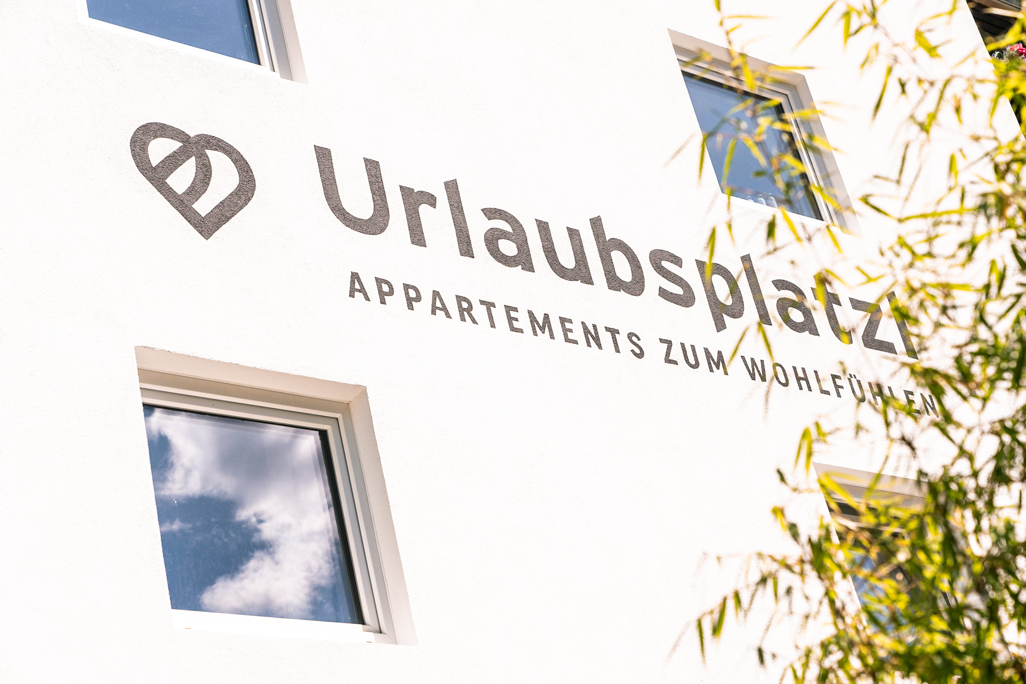 Die sonnige Fassade des Urlaubsplatzl in Oetz mit Logo-Schriftzug